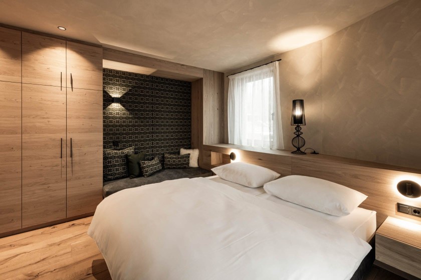 Design bedroom in natural tones, wood, white and cosy seating area