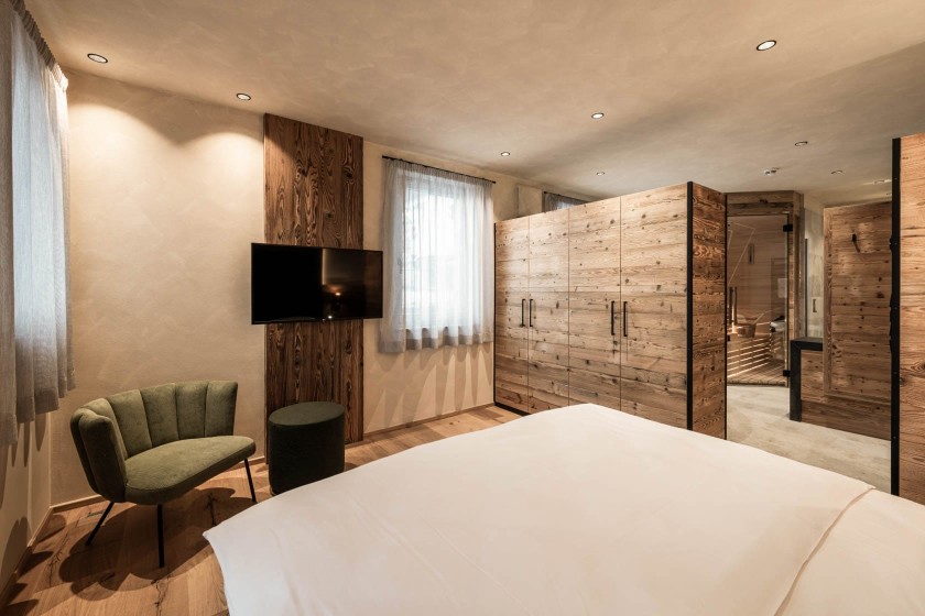 Cosy bedroom with modern design elements such as a green velvet armchair and old wood cabinets