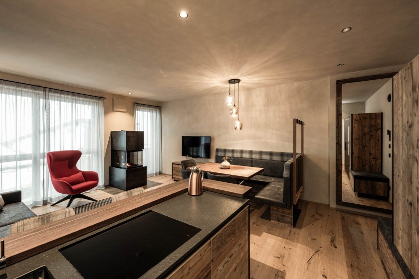 Designküche mit Stehbar zur Küche, gemütliche Sitzecke und offenem Schwedenofen und rotem Ohrensessel