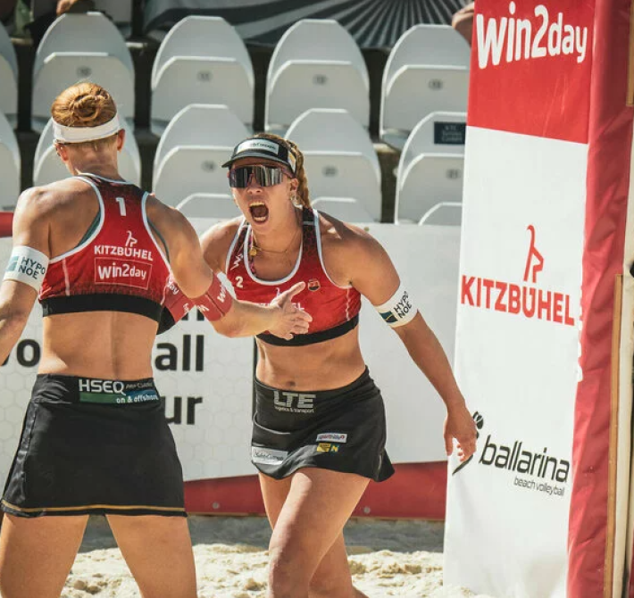 Two women are playing beach volleyball.
